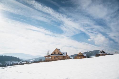 a group of buildings on top of a snow covered hill at Domek na Zawojskim Przysłopiu in Zawoja