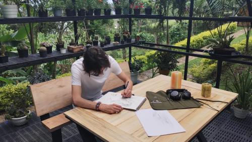 a woman sitting at a table with a book at Casa el Ocobo, proyecto ecodependiente in Silvania