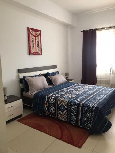 a bedroom with a bed with a blue blanket and a window at Cosy F3 au point E in Dakar
