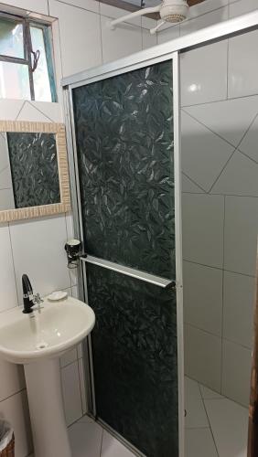 a shower with a glass door next to a sink at Pousada Sobre as Ondas - ILHA DO MEL - PR in Ilha do Mel