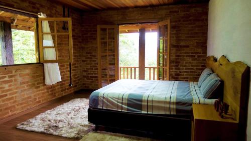a bedroom with a bed and a brick wall at Rancho Curica in Campos do Jordão