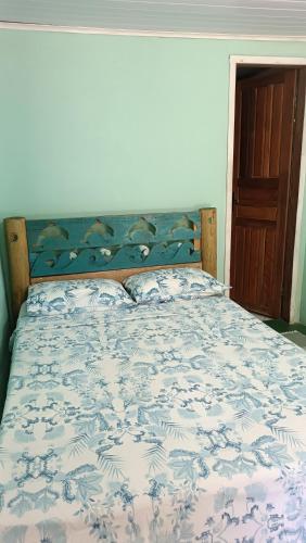 a bed in a bedroom with a blue and white bedspread at Pousada Sobre as Ondas - ILHA DO MEL - PR in Ilha do Mel