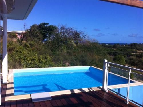 a swimming pool on the deck of a house at Villa QUIETUDE in Sainte-Anne
