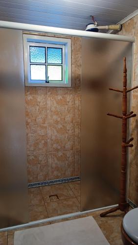 a bathroom with a sliding shower door with a window at Pousada Sobre as Ondas - ILHA DO MEL - PR in Ilha do Mel