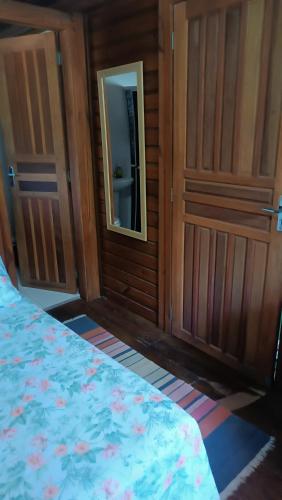 a bedroom with a bed with a mirror and a door at Pousada Sobre as Ondas - ILHA DO MEL - PR in Ilha do Mel
