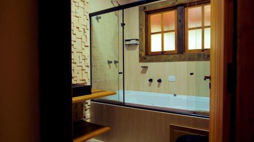a bathroom with a tub and a glass shower at Rancho Curica in Campos do Jordão