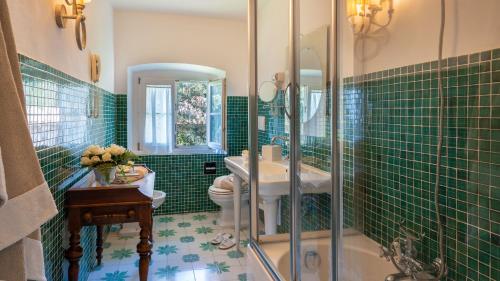 un bagno piastrellato verde con servizi igienici e lavandino di Tenuta Di Pratello 24, Emma Villas a Peccioli