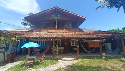 a house with an umbrella and hammocks in front of it at Pousada Sobre as Ondas - ILHA DO MEL - PR in Ilha do Mel