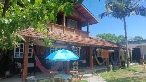 a house with a blue umbrella in front of it at Pousada Sobre as Ondas - ILHA DO MEL - PR in Ilha do Mel