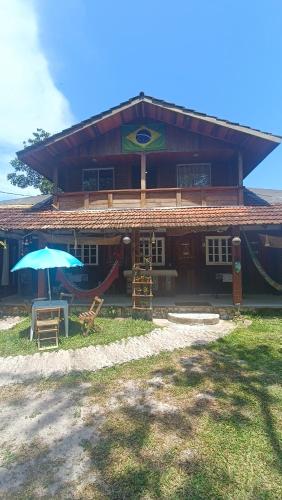 a house with an umbrella and a table and chairs at Pousada Sobre as Ondas - ILHA DO MEL - PR in Ilha do Mel