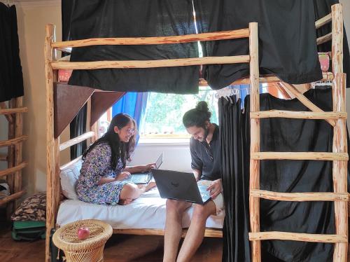 Dos personas sentadas en una cama con un ordenador portátil en The Hideout - Hiraeth en Manāli