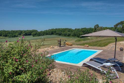 a swimming pool with two chairs and an umbrella at L'Orée du Bois du Domaine des Hauts de Rouquette in Eymet