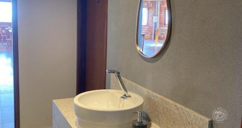 uma casa de banho com um lavatório branco e um espelho. em Pousada dos Cânticos em Barra
