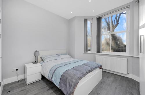 a white bedroom with a bed and a window at Your Cosy Stay Modern 3 Double Bedroom Apartment - Fully Furnished - 5 Mins walk to Stn in London