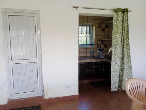 uma casa de banho com uma porta e um lavatório num quarto em Jayasri Home em Ketti