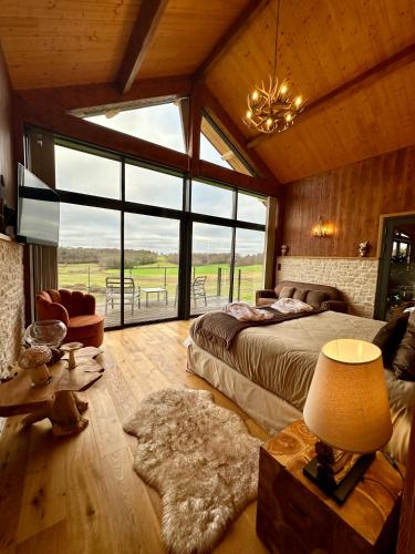 a bedroom with a bed and a large window at L'Orée du Bois du Domaine des Hauts de Rouquette in Eymet