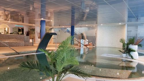 a lobby with a pool with a palm tree in it at Hotel Torresport in Torrelavega