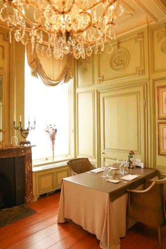 a dining room with a table and a chandelier at Hotel Recour in Poperinge