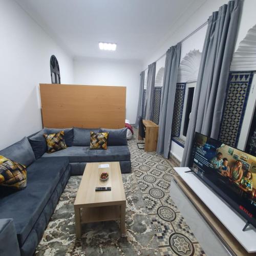 a living room with a blue couch and a tv at Riad Apartment with Panoramic Bouregreg & Marina View in Rabat