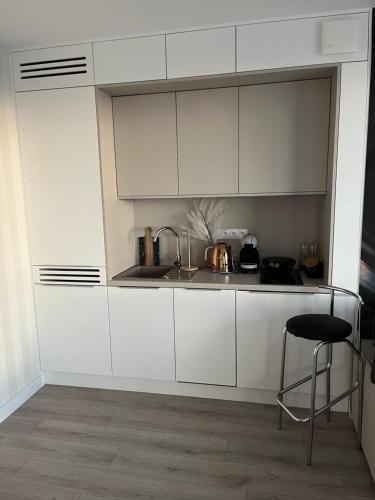 a white kitchen with a sink and a stool at AXEL WAVE Seaview Apartment &SPA in Międzyzdroje