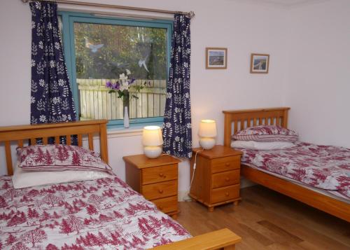 a bedroom with two twin beds and a window at Ptarmigan Cottage in Aviemore