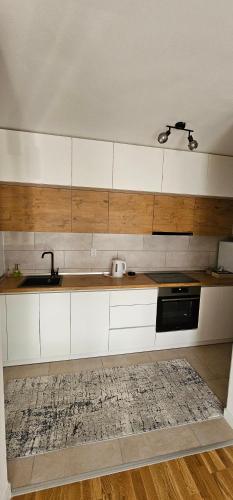 una cocina con armarios blancos y fregadero en Stan na dan-Apartman Mia, en Lukavica