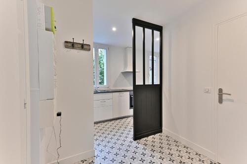 - une cuisine avec des murs blancs et une porte noire dans l'établissement Sublime 2P à 15 min du centre de Paris., à Courbevoie