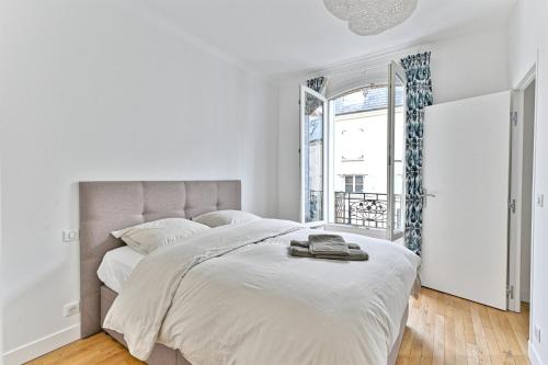 une chambre blanche avec un grand lit et une fenêtre dans l'établissement Sublime 2P à 15 min du centre de Paris., à Courbevoie