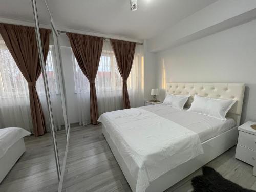 una camera bianca con un grande letto e finestre di Traveler’s Luxury Home a Suceava