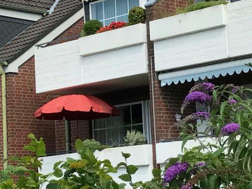 a red umbrella in front of a house with flowers at Fewo-Warns-Bad-Zwischenahn in Bad Zwischenahn