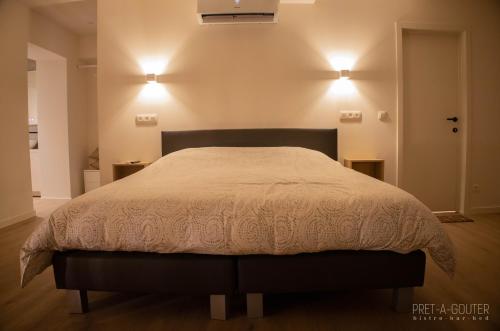 PRET A GOUTER bistro bar bed في اوسدان-زولده: سرير في غرفة نوم مع مصباحين على الحائط
