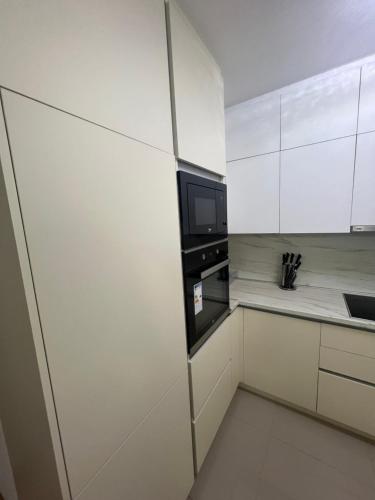 a kitchen with white cabinets and a black microwave at Downtown Apartment in Strumica