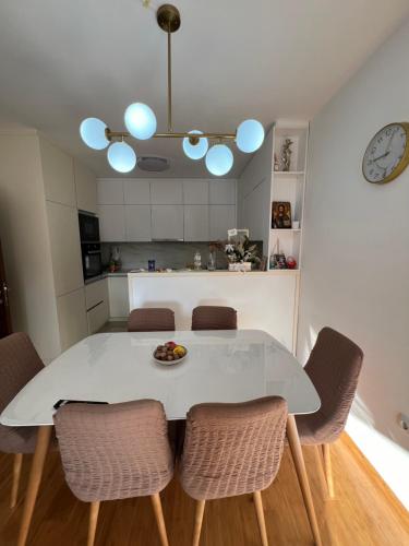 a white dining room table with chairs and a clock at Downtown Apartment in Strumica