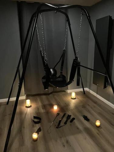 - une balançoire noire avec des lumières et des bougies sur le parquet dans l'établissement Jungle Secret SPA Nuit insolite, à Giromagny