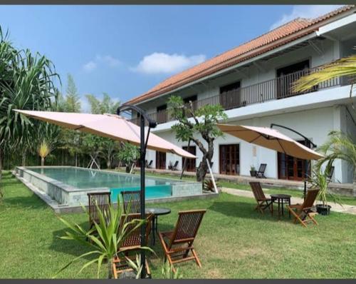 a pool with chairs and umbrellas next to a building at Tantra Hotel in Krui