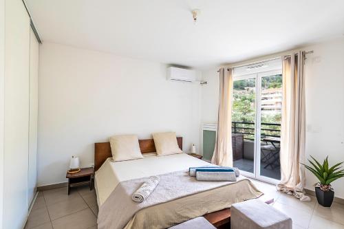 une chambre avec un lit et une grande fenêtre dans l'établissement Mare E Monte T2, à Menton