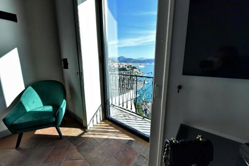 a room with a green chair and a view of the ocean at In Costa Relais & Luxury Suites in Vietri sul Mare