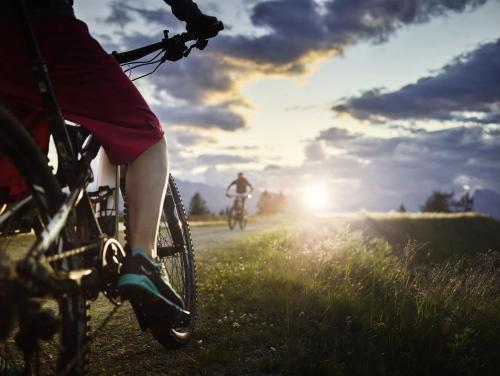a person riding a bike on a field with the sun setting at UNA RESORT in Bosanska Krupa