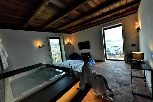 a person sitting in a bedroom next to a tub at In Costa Relais & Luxury Suites in Vietri sul Mare