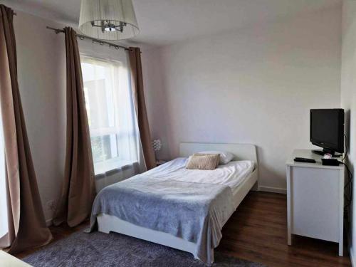 a bedroom with a bed and a tv and a window at Great Apart Mokotów in Warsaw