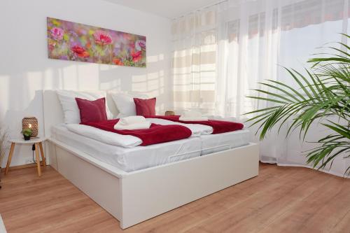 a white bedroom with a white bed with red pillows at RELAX-RED mit Pool und Sauna in Scheidegg