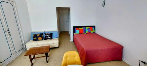 ein Schlafzimmer mit einem Bett, einem Tisch und einem Stuhl in der Unterkunft Apto vista Privilegiada da Praia in São Vicente