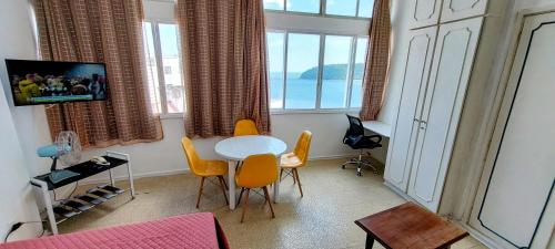 Apto vista Privilegiada da Praia في ساو فيسينتي: غرفة معيشة مع طاولة وكراسي بيضاء
