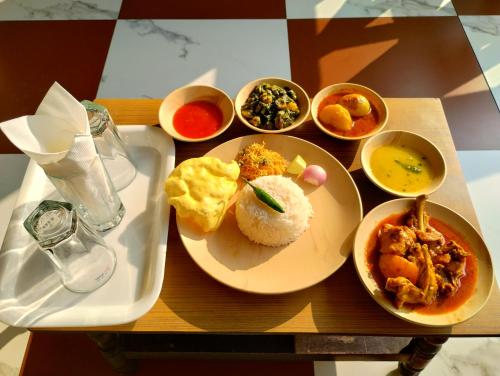 a table with plates of food and bowls of food at Muktomon Hotel & Resort in Bolpur