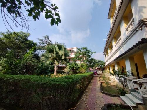a walkway next to a building with a palm tree at Muktomon Hotel & Resort in Bolpur
