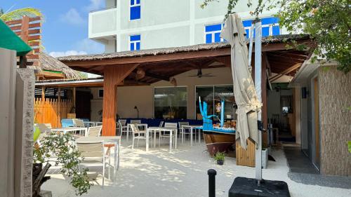 eine Terrasse mit Sonnenschirmen, Tischen und Stühlen in der Unterkunft Alimas Holiday Retreat Maldives in Felidhu-Atoll