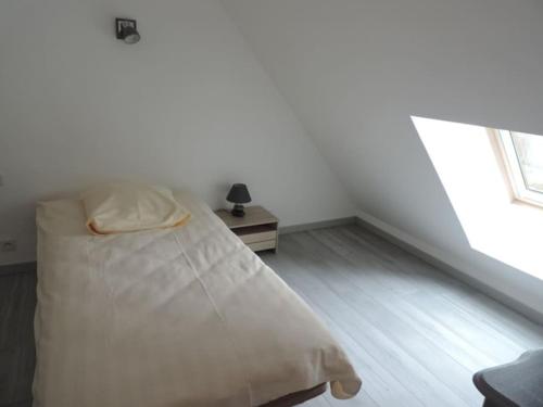 a white bedroom with a bed and a window at gîte composé de 2 maisons avec cheminée et sauna in Houdetot