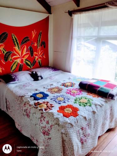 Dormitorio con cama con estampado de flores en la pared en Hospedaje familiar rural, en Quellón