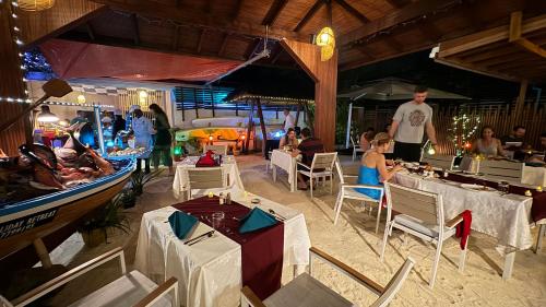 Alimas Holiday Retreat Maldives في فيليدهو: مجموعة من الناس يجلسون على الطاولات في المطعم