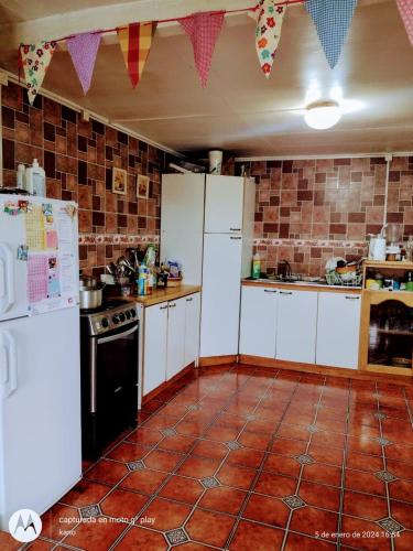 cocina con electrodomésticos blancos y suelo de baldosa roja en Hospedaje familiar rural, en Quellón